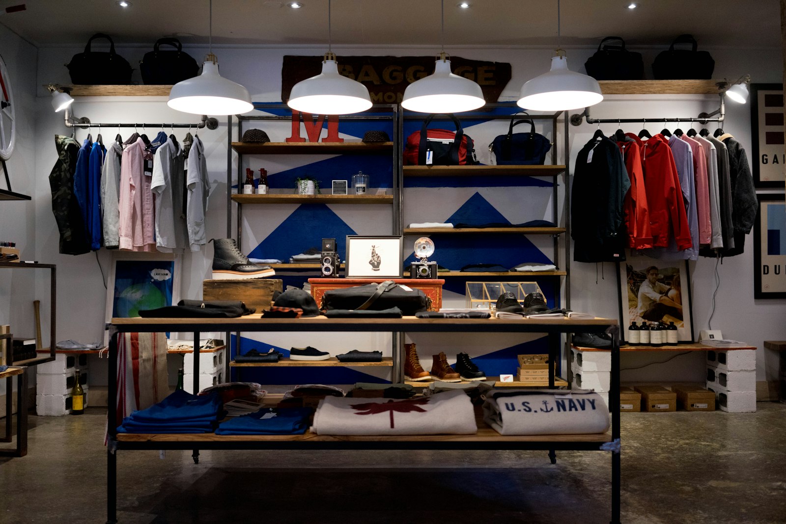 Clothing racks, folded shirts, and pendant lights inside a shop